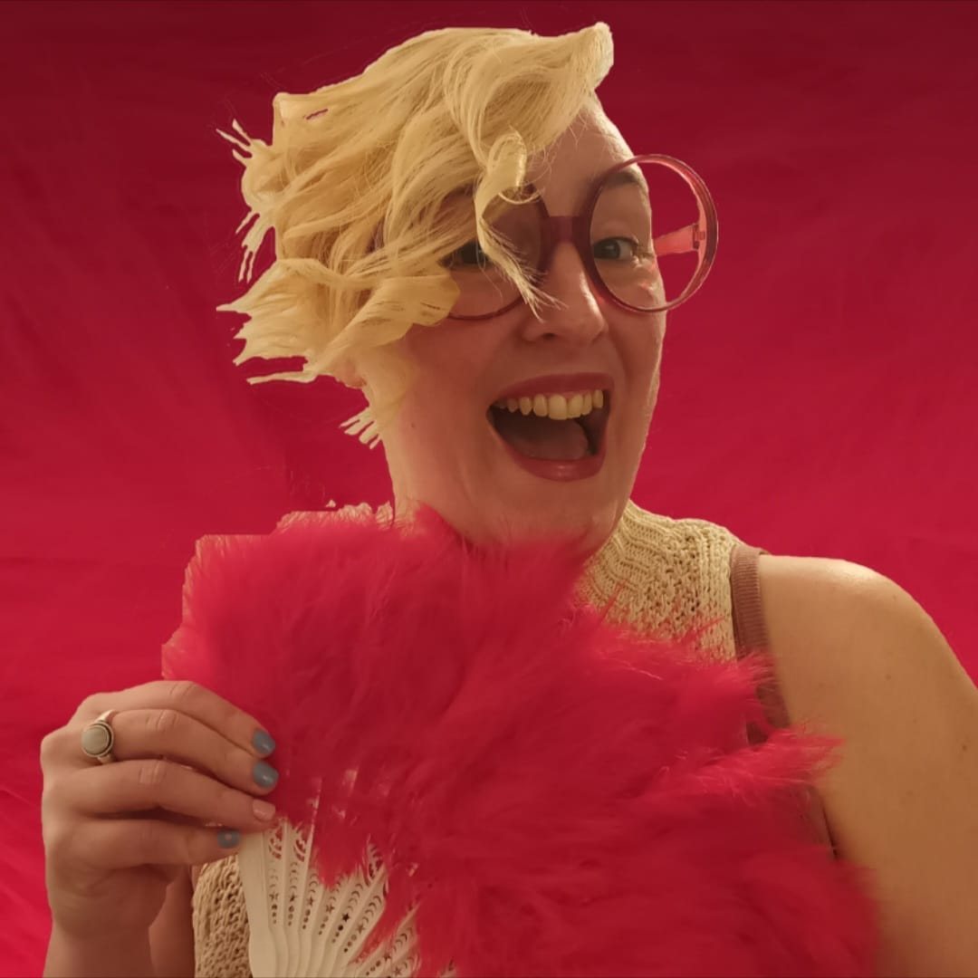Riley Bloom, souriante, un éventail de plumes à la main